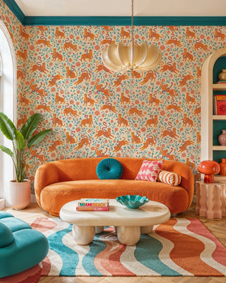 Leopard and snake wallpaper with folk florals on ivory, in a vibrant living room with orange curved sofa