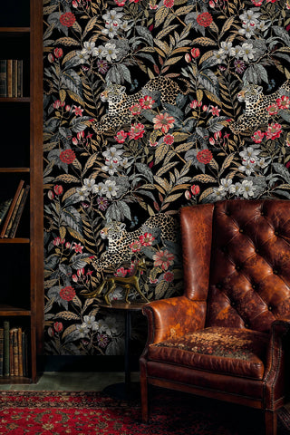 Leopard botanical wallpaper featuring spotted cats among tropical blooms, displayed in library with leather chair