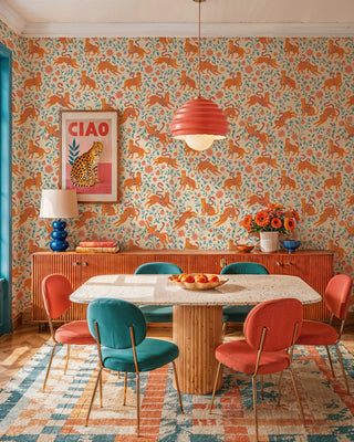 Leopard floral wallpaper with orange cats and teal vines on cream, in a dining room with coral pendant lamp