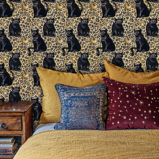 Luxurious cat and cocktail wallpaper with leopard spots shown in cozy bedroom with vintage nightstand