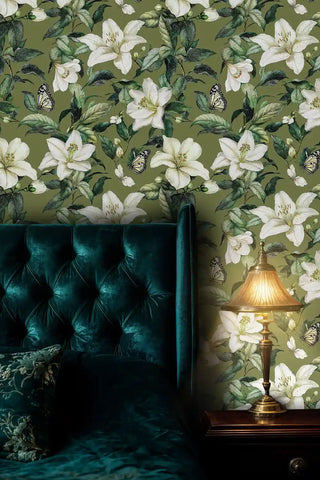 Luxurious lily wallpaper in sage green, displayed behind emerald velvet tufted chair with brass lamp