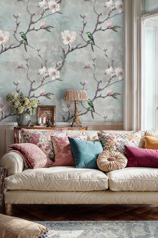 Magnolia blossom wallpaper with green birds on grey background in elegant living room with cream sofa