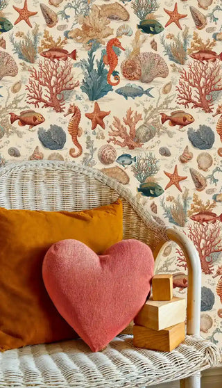 Marine adventure wallpaper with tropical fish and shells, displayed in nursery with wicker chair and coral pillow