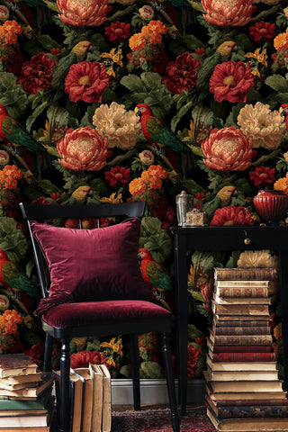 Maximalist parrot wallpaper with coral peonies and exotic birds, in cozy reading nook with book stacks