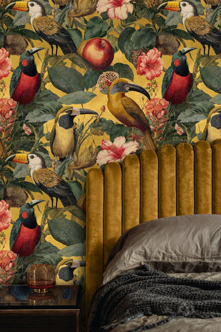 Maximalist toucan wallpaper with pink flowers on gold, in a bedroom with channel-tufted velvet headboard