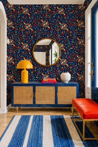 Medieval ornamental wallpaper in navy and red with moon motifs, in an entryway with round mirror