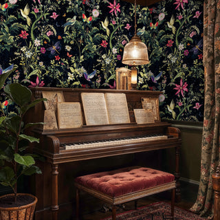 Midnight floral wallpaper with hummingbirds and butterflies, shown in music room with vintage piano and red velvet bench