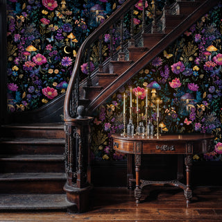 Midnight garden wallpaper with butterflies and moon motifs, shown in grand entryway with curved staircase