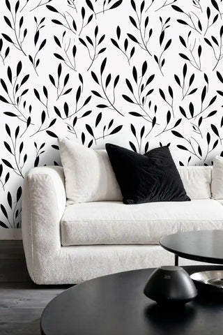 Minimalist botanical wallpaper featuring black leaf branches in modern living room with light sofa