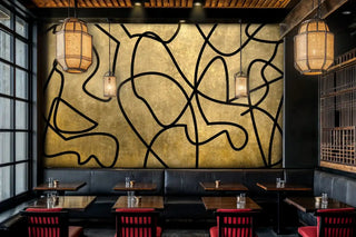 Modern abstract wall mural featuring interweaving black lines on gold, shown in restaurant with pendant lights