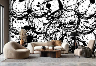 Modern paint splash wallpaper in black and white, displayed in living room with curved beige sofa and wooden table
