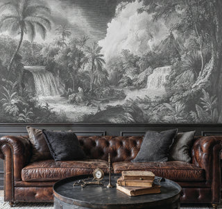 Monochrome jungle wall mural with cascading waterfalls and lush foliage, in a dark living room with leather Chesterfield sofa