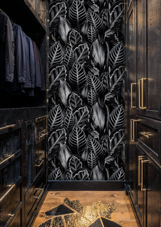 Monochrome leaf pattern wallpaper on black, inside a luxury walk-in closet with brass hardware