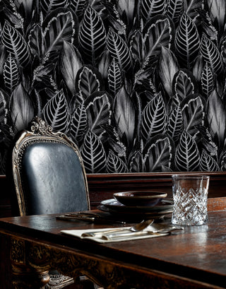 Monochrome tropical leaf wallpaper on black, in an elegant dining room with ornate gilded chair