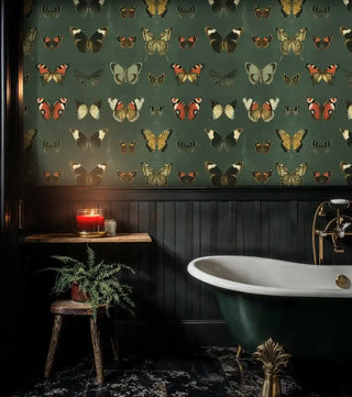 Moody butterfly collection wallpaper in a dark bathroom with black wainscoting and a classic freestanding bathtub.