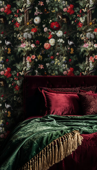 Moody floral wallpaper with birds and squirrels on black, behind a velvet bed with green tasseled throw