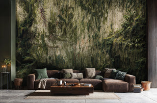 Moss-covered rock wall mural with lush greenery, in an open living room with brown leather sectional and candles