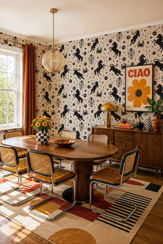 Mystical animal wallpaper with black horses and crabs on beige, in a retro dining room with cane chairs