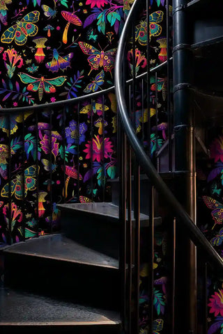 Mystical butterfly wallpaper with colorful moths and wildflowers on black, shown on dramatic stairway with brass railings