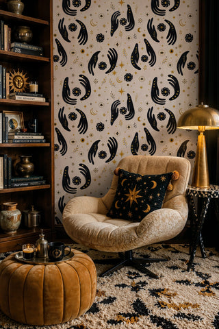 Mystical dark hands wallpaper with moons and stars shown in a cozy reading nook with bookshelf and armchair
