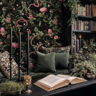 Mystical garden wallpaper with serpents and flowers, in cozy reading nook with candlelight and old books