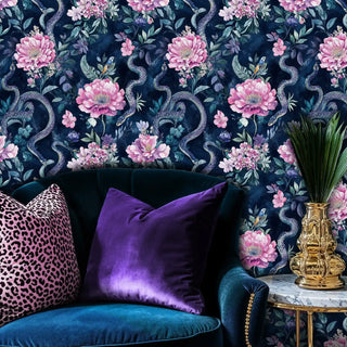 Navy botanical wallpaper featuring serpents and pink flowers, displayed in glamorous seating area with velvet cushions