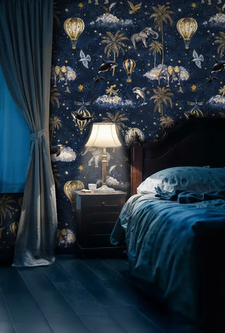 Navy celestial adventure wallpaper featuring golden balloons and elephants, shown in cozy bedroom setting