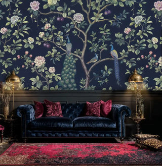 Navy peacock garden wallpaper in elegant living room with burgundy velvet pillows and gold accents