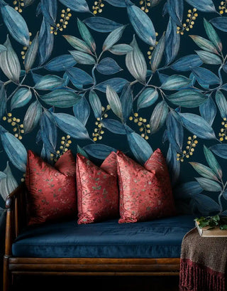 Navy teal botanical leaf wallpaper with gold berries, behind a wooden bench with red cushions
