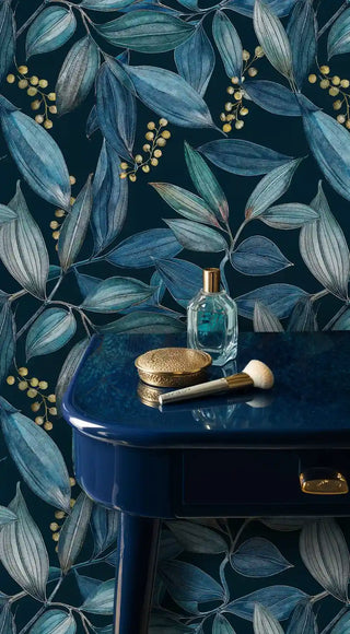 Navy teal botanical leaf wallpaper with gold berries, styled with a blue vanity and perfume