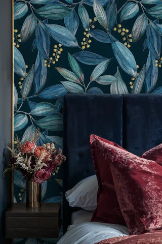 Navy teal botanical leaves wallpaper with gold berries by a velvet headboard