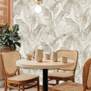 Neutral leaf pattern wallpaper with organic textures, displayed in modern dining nook with cane-back chairs