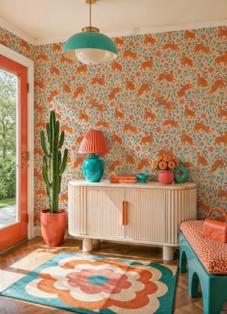 Orange leopard wallpaper with snakes and botanicals, in a bright entryway with tall cactus and ribbed credenza