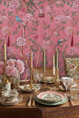 Chinoiserie wallpaper with birds and peonies on coral background, shown in cozy bedroom with cream bedding
