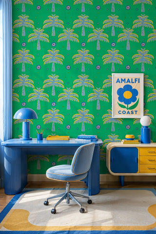 Palm tree repeat wallpaper in vivid green styled in a retro home office with fluted blue desk