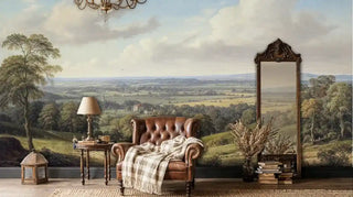 Pastoral landscape wall mural featuring rolling hills and trees, shown in cozy reading nook