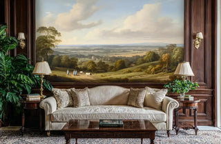 Pastoral landscape wall mural showing rolling hills and trees in sophisticated living room with beige sofa