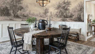 Pastoral landscape wallpaper in sepia and ivory with rolling meadows, displayed in rustic dining room with round table
