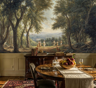 Pastoral woodland wall mural with dancing figures and ancient trees, displayed in rustic dining room with wooden table