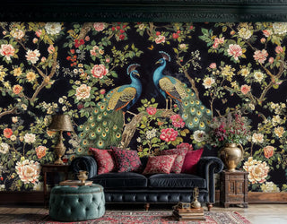 Peacock floral wallpaper with blue birds and coral blooms on black, shown in elegant living room with leather sofa