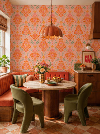Pink and orange celestial damask wallpaper with green foliage, in a dining nook with marble round table