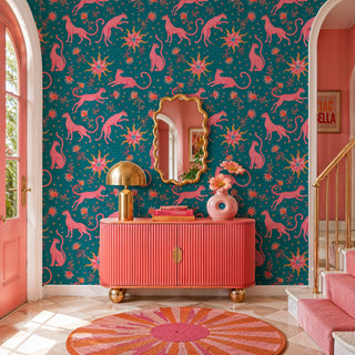 Pink leopard celestial wallpaper with sun motifs on teal, in a glam entryway with gold mirror and coral console