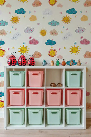 Playful sun and cloud pattern wallpaper in bright colors, shown in kids room with colorful storage cubes