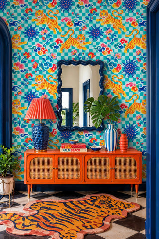 Playful tiger checkered wallpaper with vibrant clouds, in an entryway with orange credenza and wavy mirror