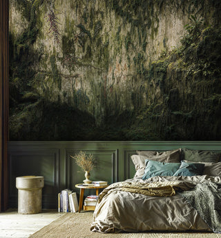 Rainforest cliff wall mural with cascading moss, above green wainscoting in a bedroom with concrete side table