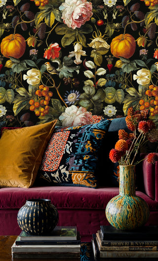 Rich botanical wallpaper featuring harvest florals on black background in vibrant living room with burgundy velvet sofa