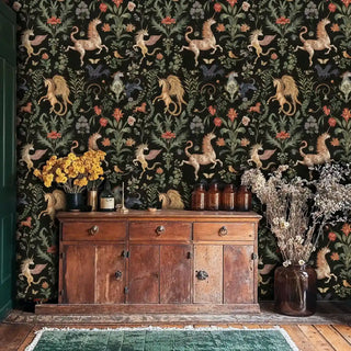 rich unicorn and botanical wallpaper in black and gold, shown above a rustic wooden sideboard with dried floral arrangement