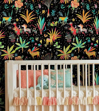 Safari animal wallpaper with colorful deer and tropical florals on black, displayed in nursery with white crib and coral bedding
