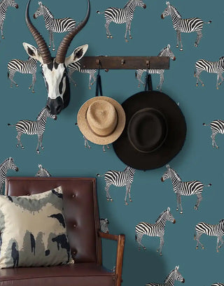 Safari animal wallpaper with zebra stripes on teal backdrop, styled in entryway with antelope mount and hanging hats