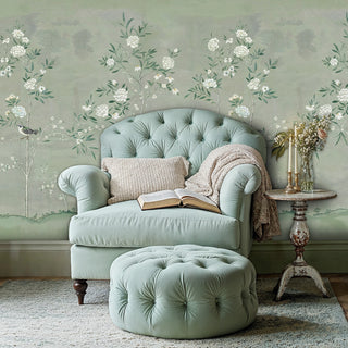 Sage botanical wallpaper featuring white peonies and birds in cozy reading nook with tufted armchair